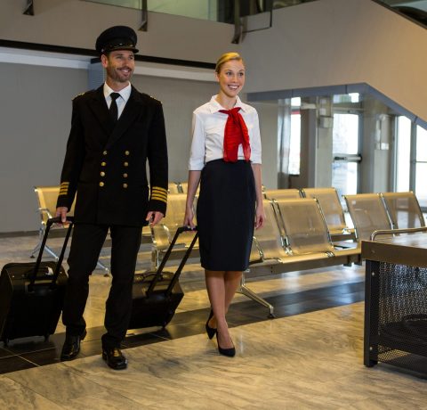Pilot and air hostess walking with their trolley bags in the airport terminal